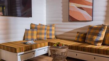 Una habitación acogedora con sofá cama, una mesita con un frutero y un televisor montado en la pared.