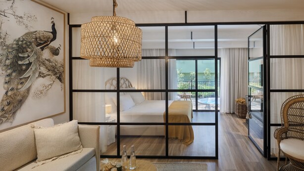 Een moderne hotelkamer met een groot raam, een bed, een slaapbank en een eethoek.