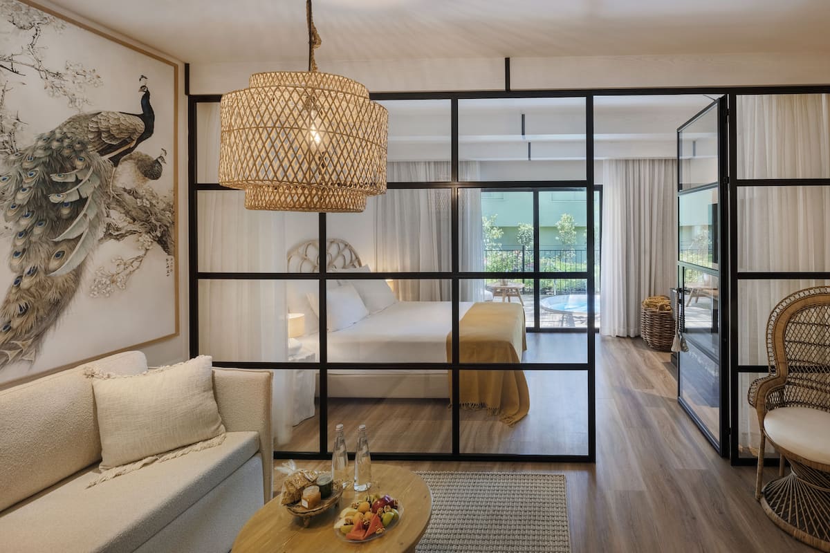 Een moderne hotelkamer met een groot raam, een bed, een slaapbank en een eethoek.