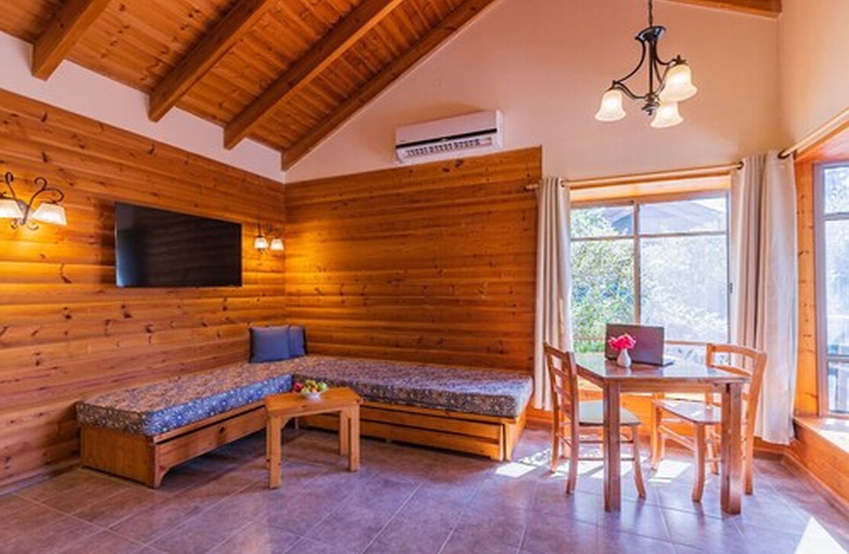 A cozy wooden cabin interior with a sofa, a dining table, and chairs.