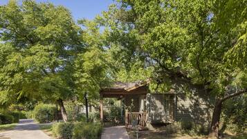 A rustic cabin with a porch, surrounded by lush greenery and trees.