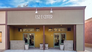A building with the sign "132 E CENTER" above the entrance. There are two doors, each with a window above. The building has a beige facade with a brown trim. - Downtown Hideaway in the Heart of Moab #2 (Moab)