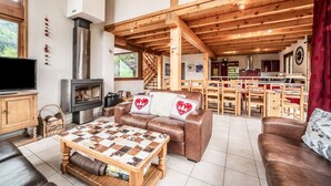 Ein gemütliches Wohnzimmer mit Kamin, Holzboden und einem Essbereich mit Holzzmöbeln.