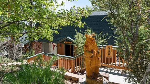 Une cabane en bois avec une véranda, une clôture en bois et le tronc d’un arbre.