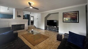 Een moderne woonkamer met een flatscreen televisie, een glazen salontafel en een open haard.