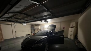 Een auto geparkeerd in een garage met weinig licht, met een stopbord aan de muur.