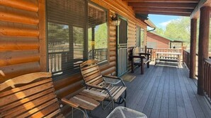Une véranda abritée avec des bancs en bois et une table, de grandes fenêtres et une vue sur le paysage environnant.