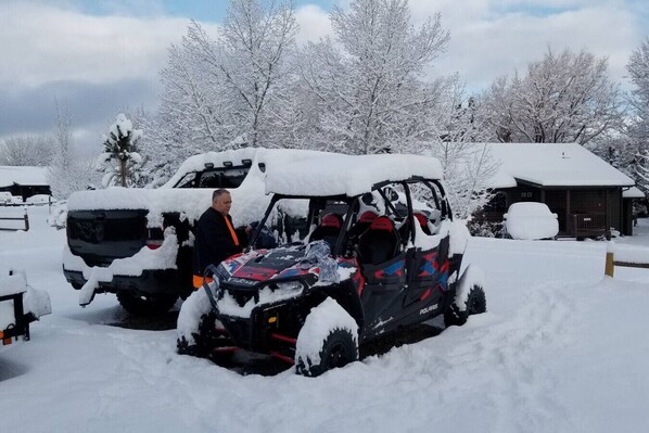 A snow-covered landscape with a Polaris snowmobile parked in front of a building. - Cozy Bear Cabin with Hot Tub (overgaard)