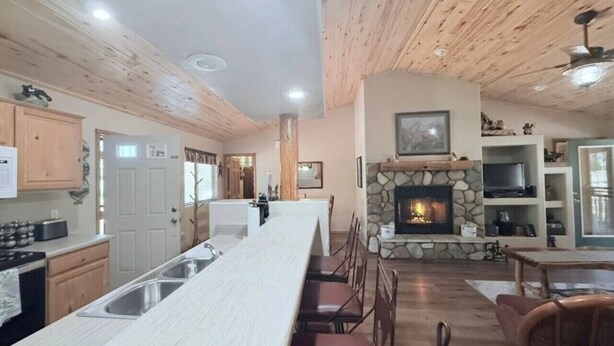 Une cuisine spacieuse avec un grand îlot central, un plafond en bois et une cheminée en pierre.