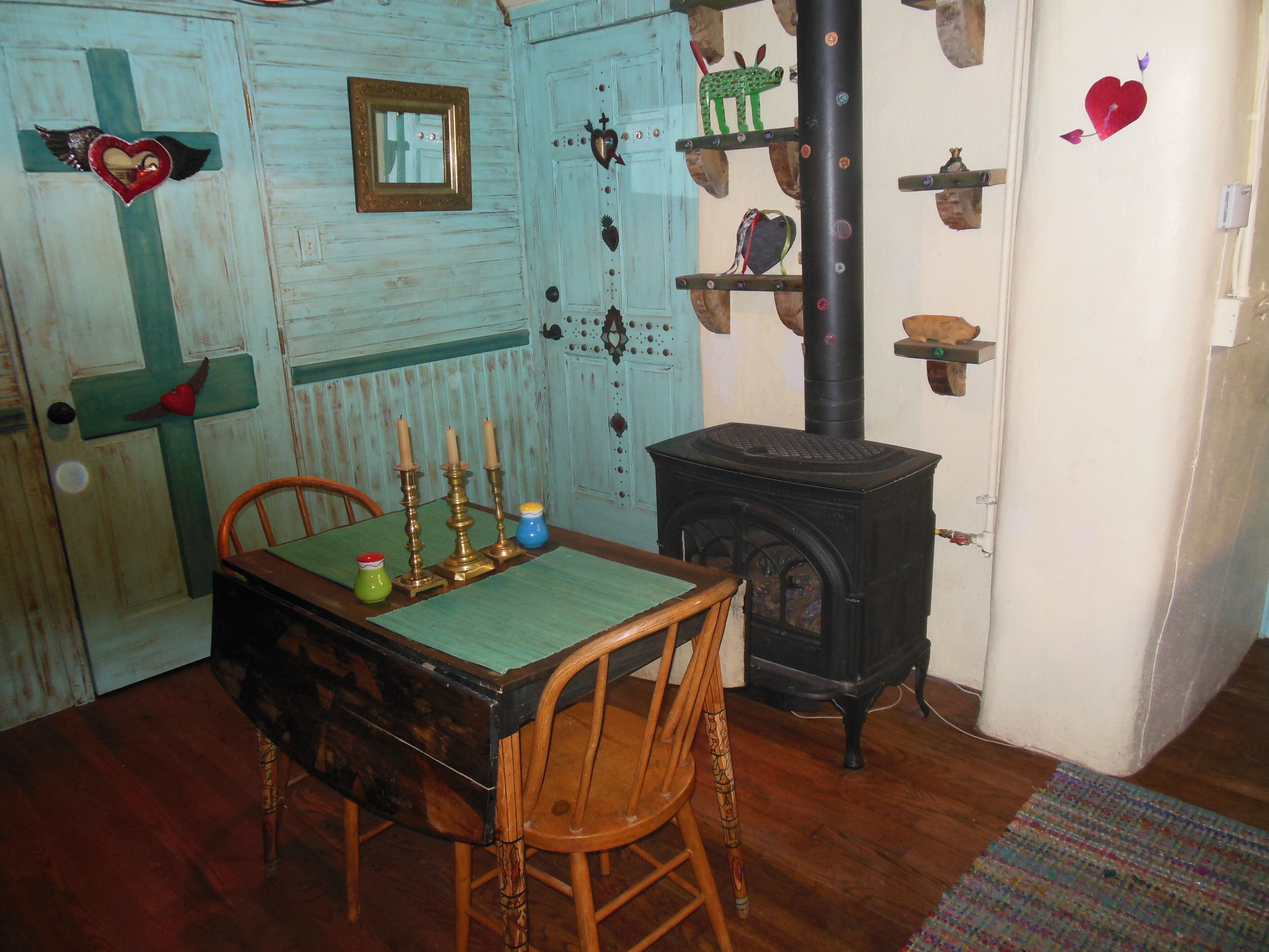 A rustic room with a wooden table, chairs, a stove, and decorative items on the walls.