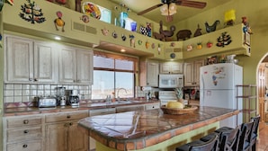 A kitchen with a central island, wooden cabinets, and a variety of decorative items on the walls. - Ocean view 6 bedroom 4 bath 3500 square foot  (Puerto Penasco)