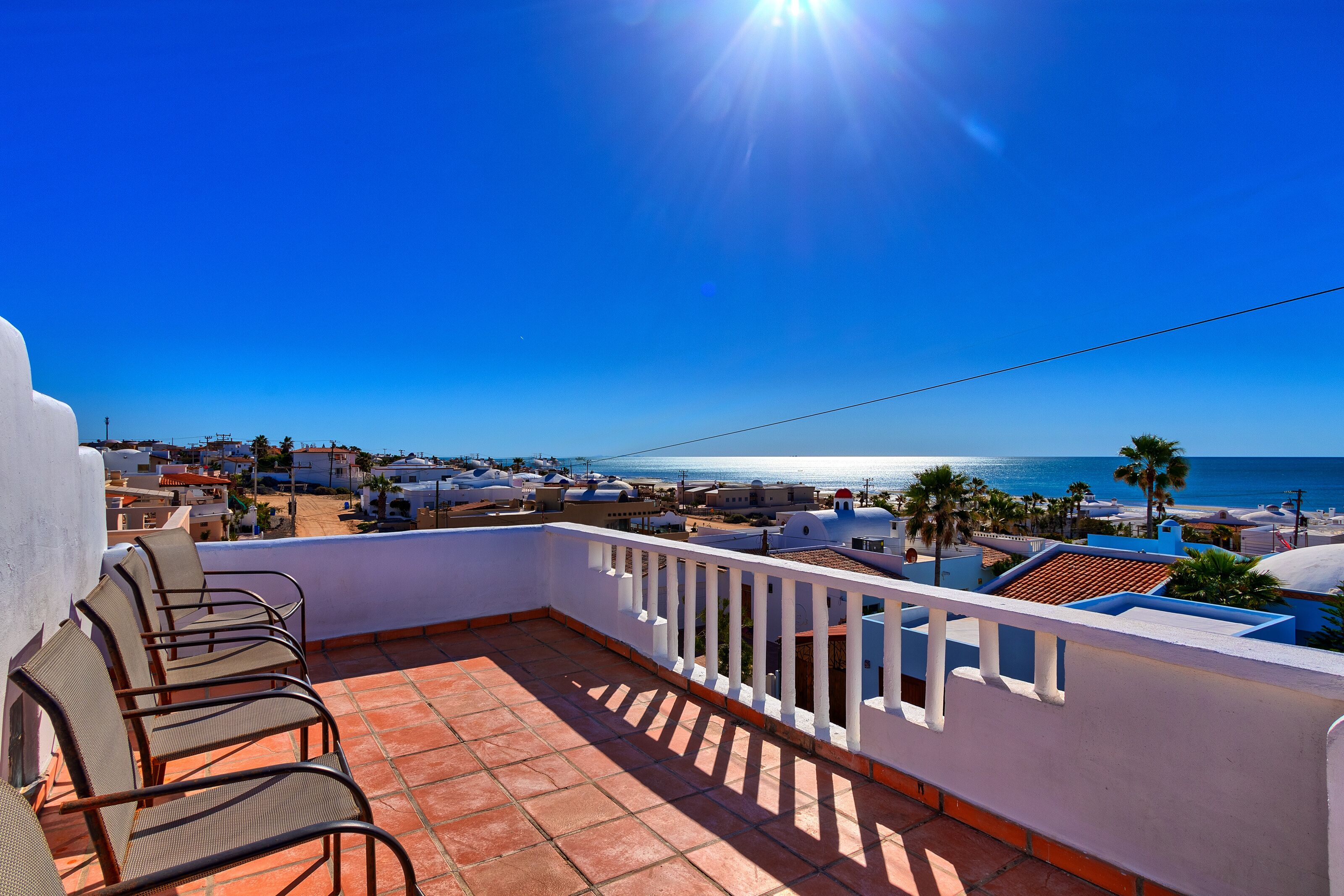 A balcony with chairs overlooking a coastal view.