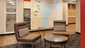 A lobby with two leather armchairs, a small table, and a large map on the wall. - TownePlace Suites by Marriott Titusville Kennedy Space Center (Titusville)