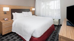 A hotel room with a large bed, two bedside tables with lamps, a TV, and a window with sheer curtains. - TownePlace Suites by Marriott Titusville Kennedy Space Center (Titusville)