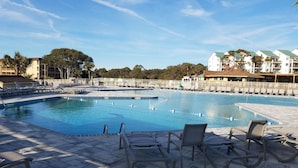 Ein Schwimmbecken mit Liegestühlen und einer gefliesten Poolterrasse.