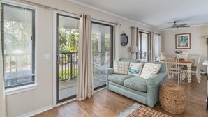 Ein Wohnzimmer mit Sofa, Esstisch und Balkon mit Schiebeglasfenstern.