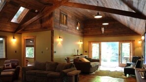 L’intérieur chaleureux d’un chalet avec un plancher en bois, un canapé, une table à manger et une cheminée.