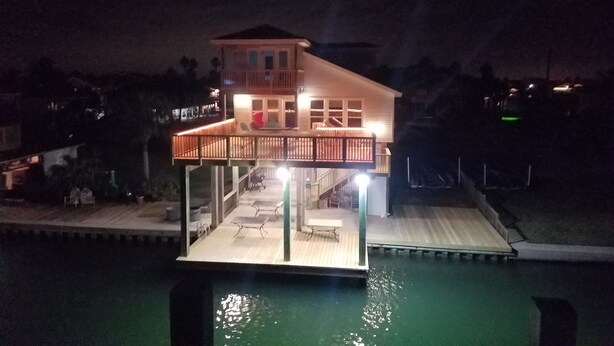 A two-story house with a balcony, a pool, and outdoor furniture.
