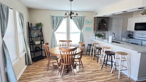 A kitchen with a central island, wooden chairs, and a dining table.
