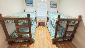 A room with two bunk beds, a small table, and a ceiling fan.