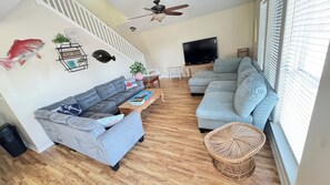 A living room with two sofas, a TV, and a ceiling fan.
