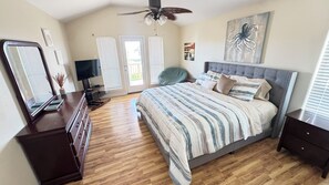 A bedroom with a bed, a dresser, a television, and a ceiling fan.