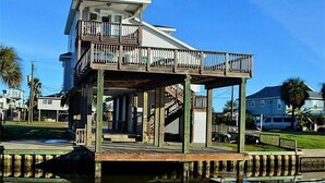 A two-story waterfront house with a balcony and a dock extending into the water.