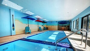 An indoor swimming pool with clear blue water, surrounded by blue chairs and umbrellas, and a view of the outside through large windows. - Roomy 2BR/2BA in Keystone (Keystone)