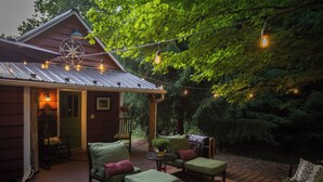 Eine Holzhütte mit Veranda, Sitzgelegenheit im Freien und Lichterketten.