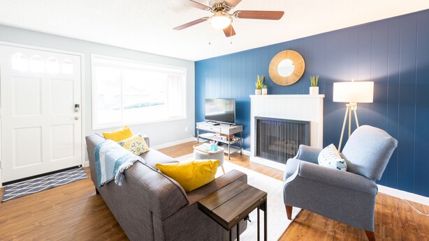 A living room with a sofa, armchair, TV stand, and fireplace. - Bright*Private*Stylish 2BR Flat W/ Fenced Yard Near Washington Square (Tigard)