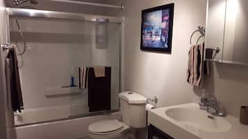 Een bad/douchecombinatie, een haardroger, handdoeken, zeep