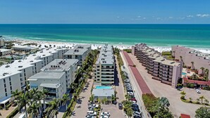 A coastal hotel with multiple buildings, a parking lot, and a beach in the background. - On the Beach! Updated 2bd/2bth. Escape the cold, spend Christmas in Paradise! (Siesta Key)