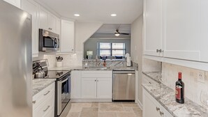 A modern kitchen with white cabinetry, stainless steel appliances, and a marble countertop. - On the Beach! Updated 2bd/2bth. Escape the cold, spend Christmas in Paradise! (Siesta Key)