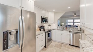 A modern kitchen with stainless steel appliances, white cabinetry, and a marble countertop. - On the Beach! Updated 2bd/2bth. Escape the cold, spend Christmas in Paradise! (Siesta Key)