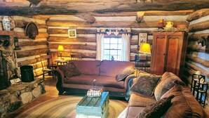 Ein gemütliches Blockhaus-Interieur mit einer Holzbank, einem Couchtisch und einem Kamin.