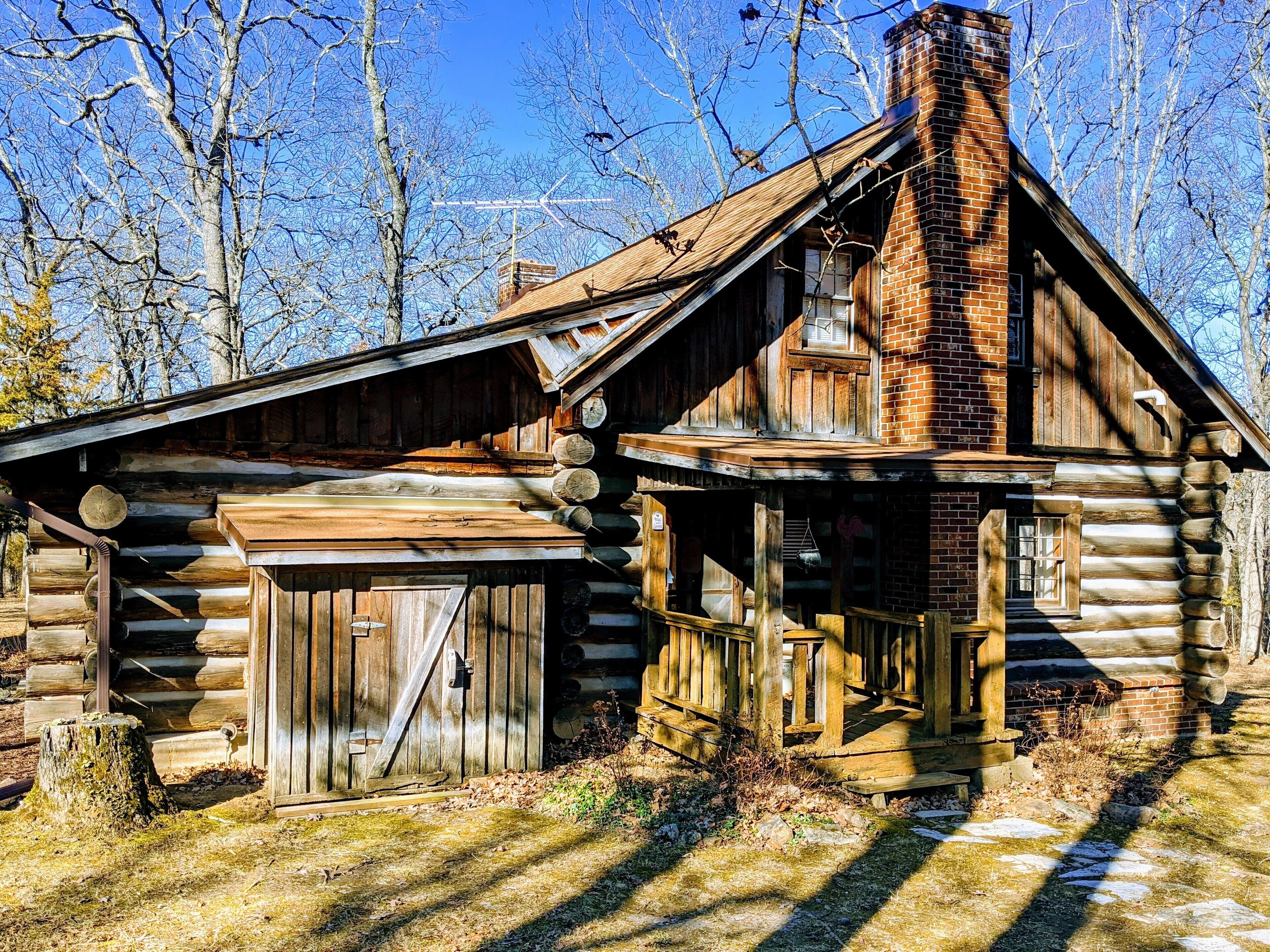 A rustic log cabin with a wooden porch and a chimney.
