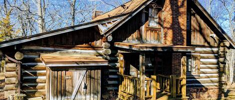 A rustic log cabin with a wooden porch and a chimney.