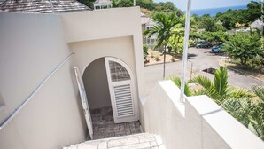 A view from a balcony overlooking a street with parked cars and palm trees. - Spectaculer View at Columbus Heights (Ocho Rios)