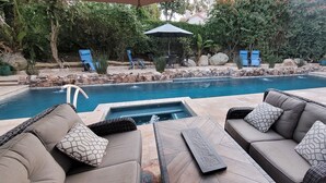 Un espace piscine doté d’un jacuzzi, de chaises longues et d’un mur en pierre.