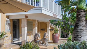 Fachada de edificio de piedra, con un balcón y dos estatuas de leones.