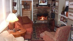 Un salon chaleureux avec une cheminée, un téléviseur et un coin salon confortable.