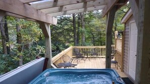 Un bain à remous doté d’une terrasse en bois et de mobilier d’extérieur, le tout entouré d’arbres.