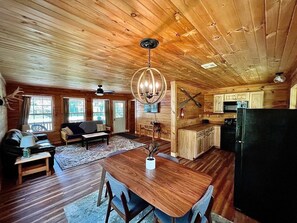 Ein Holzblockbau-Innenraum mit Essbereich, Küche und Wohnzimmer.