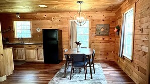 L’intérieur d’un chalet en bois comprend une cuisine, un coin repas et une grande fenêtre.
