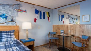 Ein Zimmer mit einem Bett, einem Tisch mit Stühlen, einer Lampe und einem Spiegel.