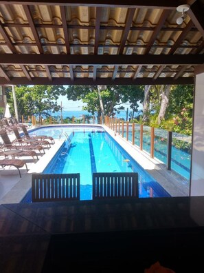 A swimming pool with lounge chairs and a view of the ocean.
