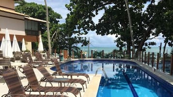 Una piscina techada, una piscina al aire libre, sombrillas