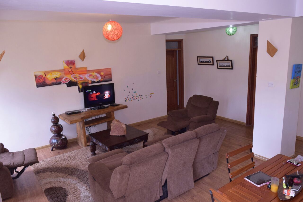 Ein Wohnzimmer mit einer Couch, einem Couchtisch, einem Fernseher und einer dekorativen Vase.