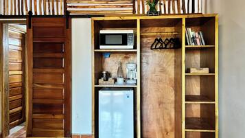 Una cocina compacta con microondas, cafetera y refrigerador.