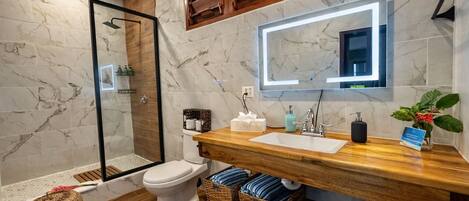 Un baño moderno con ducha, inodoro y tocador con espejo.